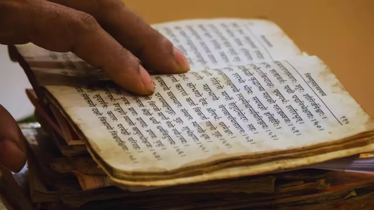 person reading a book that is in sanskrit